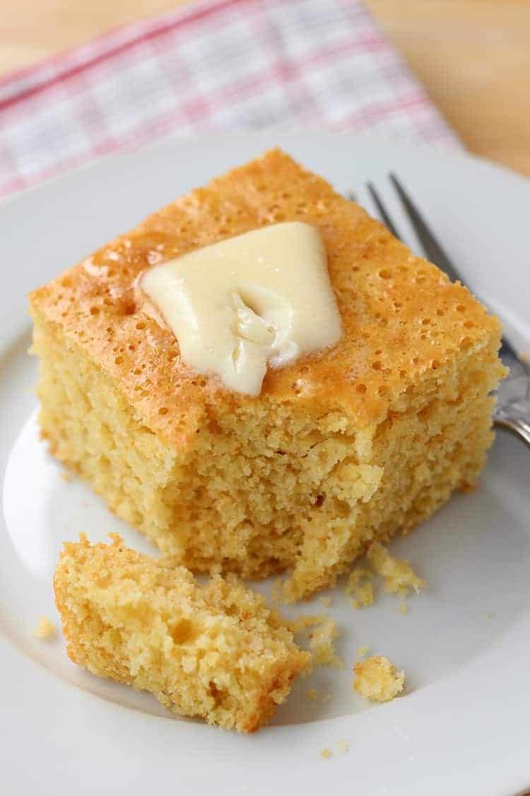 Close up of piece of cornbread with pat of butter melting on top.