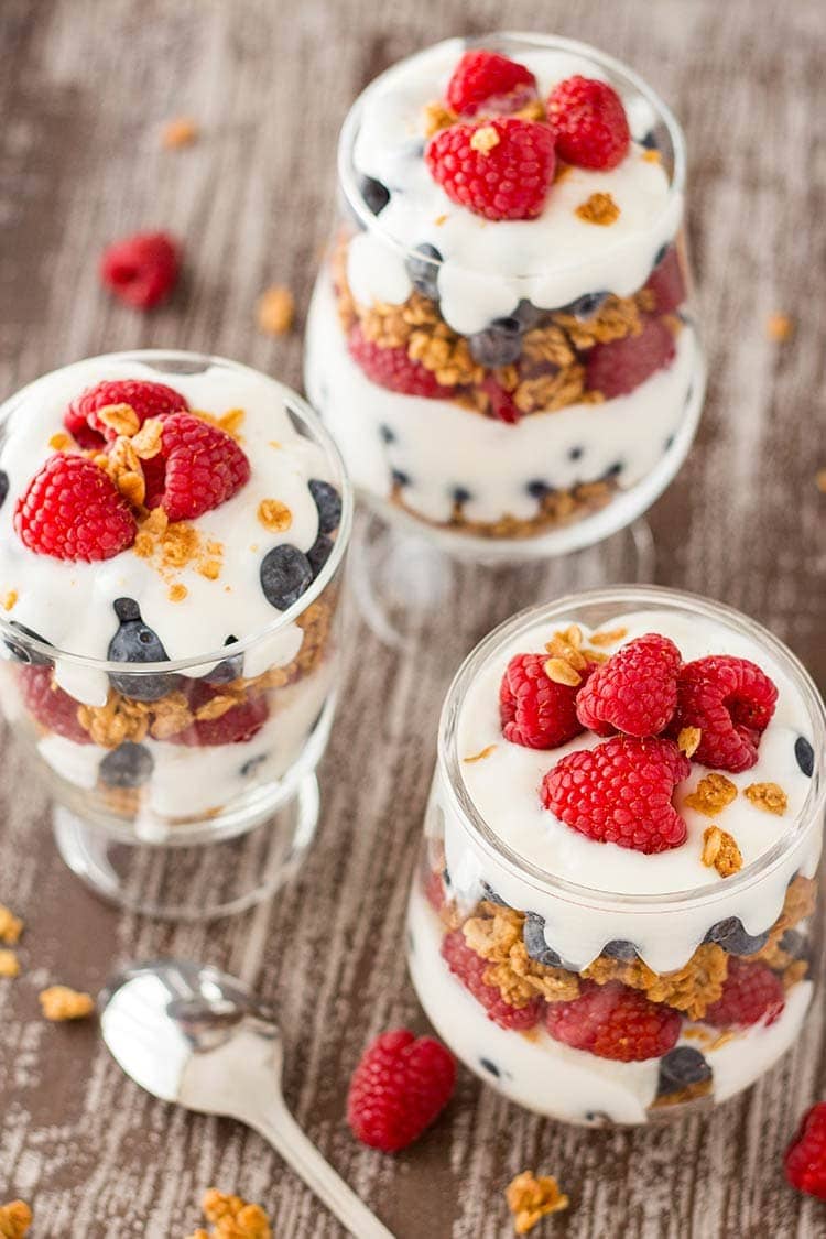 Trio of jars filled with Easy Granola Parfaits, made with granola, blueberries, raspberries and yogurt.