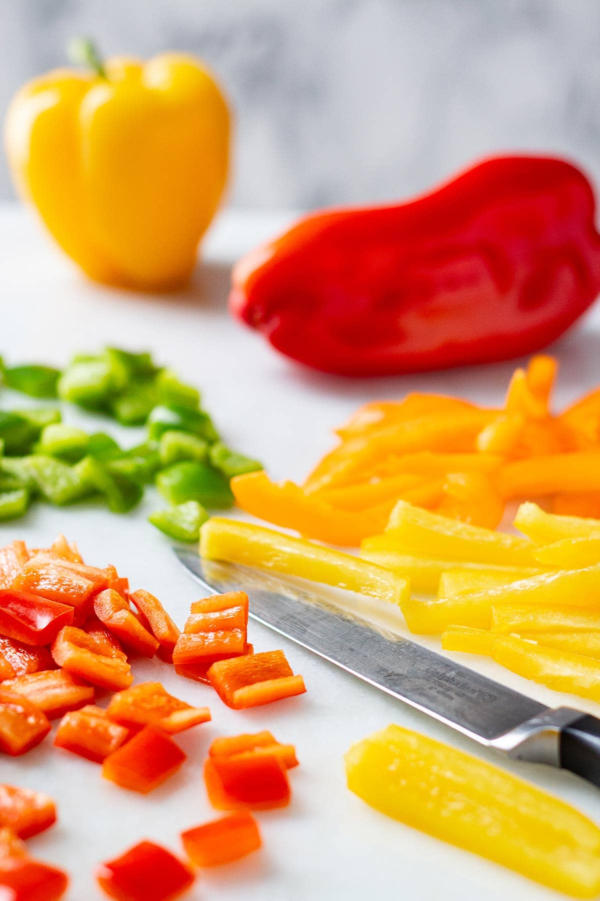 Diced and sliced bell peppers on a white countertop.