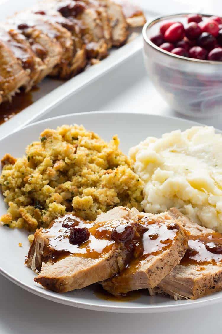 Spiced Cranberry Pork Roast dished up on a plate for a meal with mashed potatoes and stuffing
