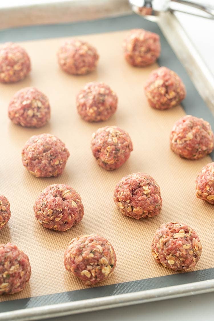 Easy Baked Freezer Meatballs portioned into balls on a baking tray and ready to be put in the oven.
