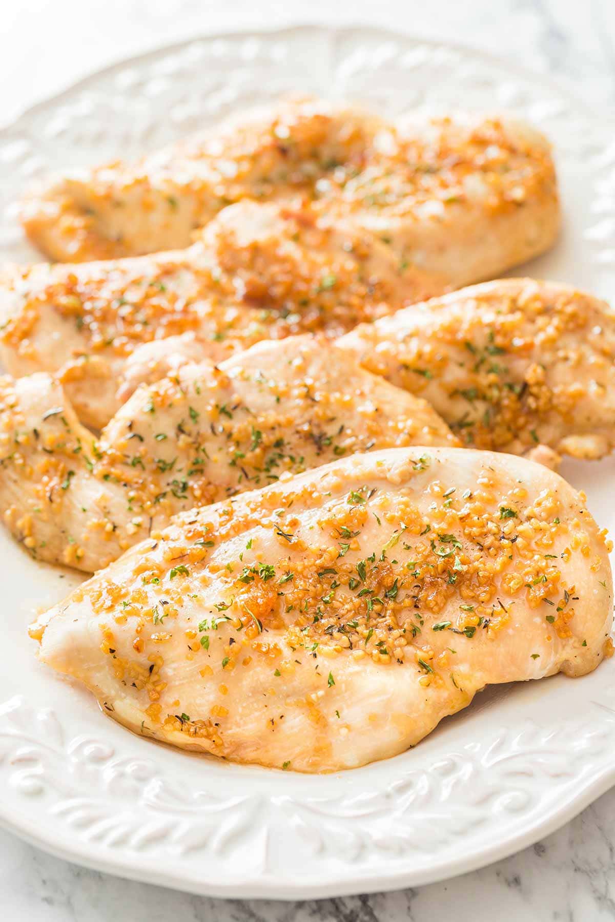 White platter with boneless skinless chicken breasts baked with garlic and brown sugar.