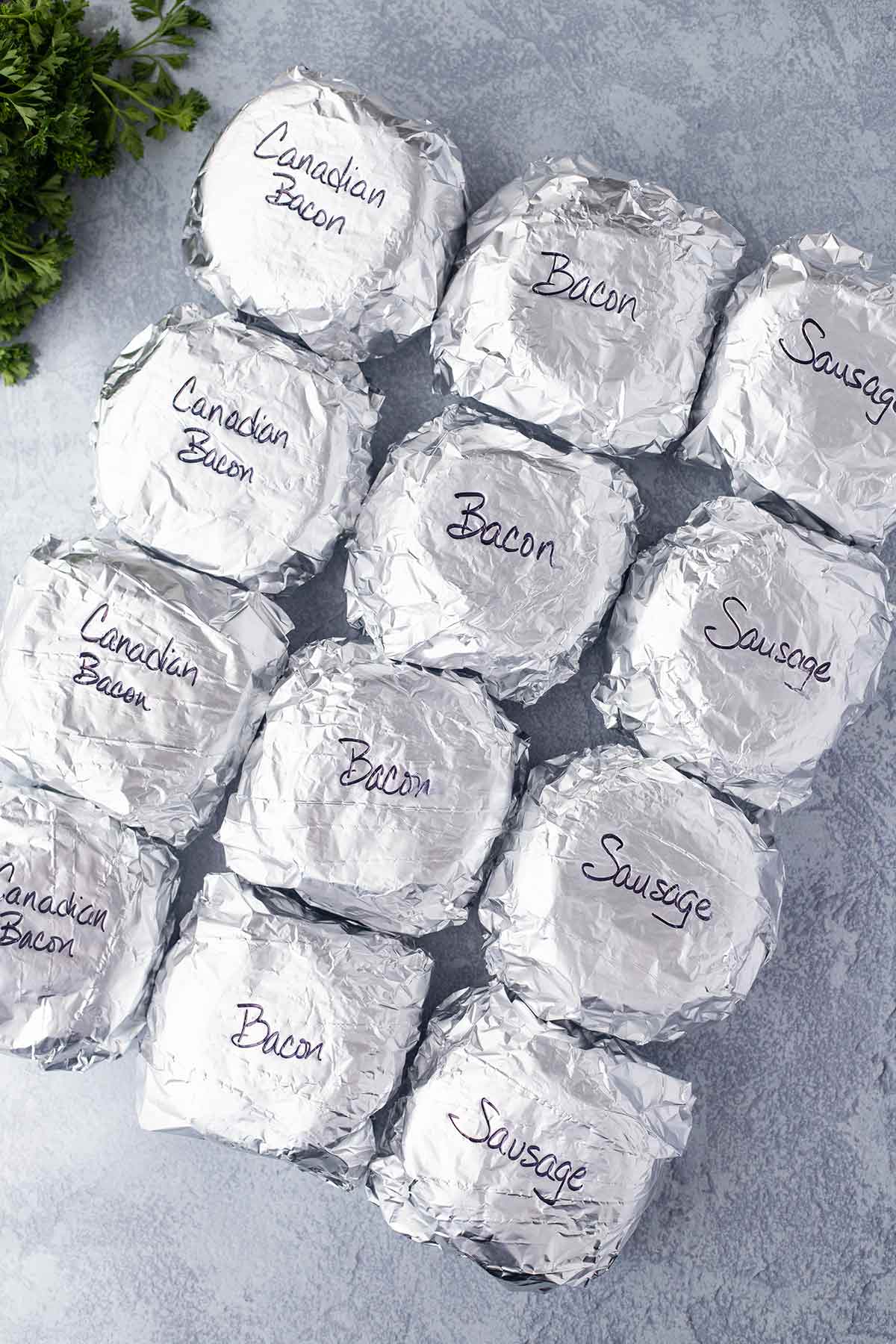 Overhead shot showing a dozen wrapped sandwiches that have been labeled according to the type of meat used.